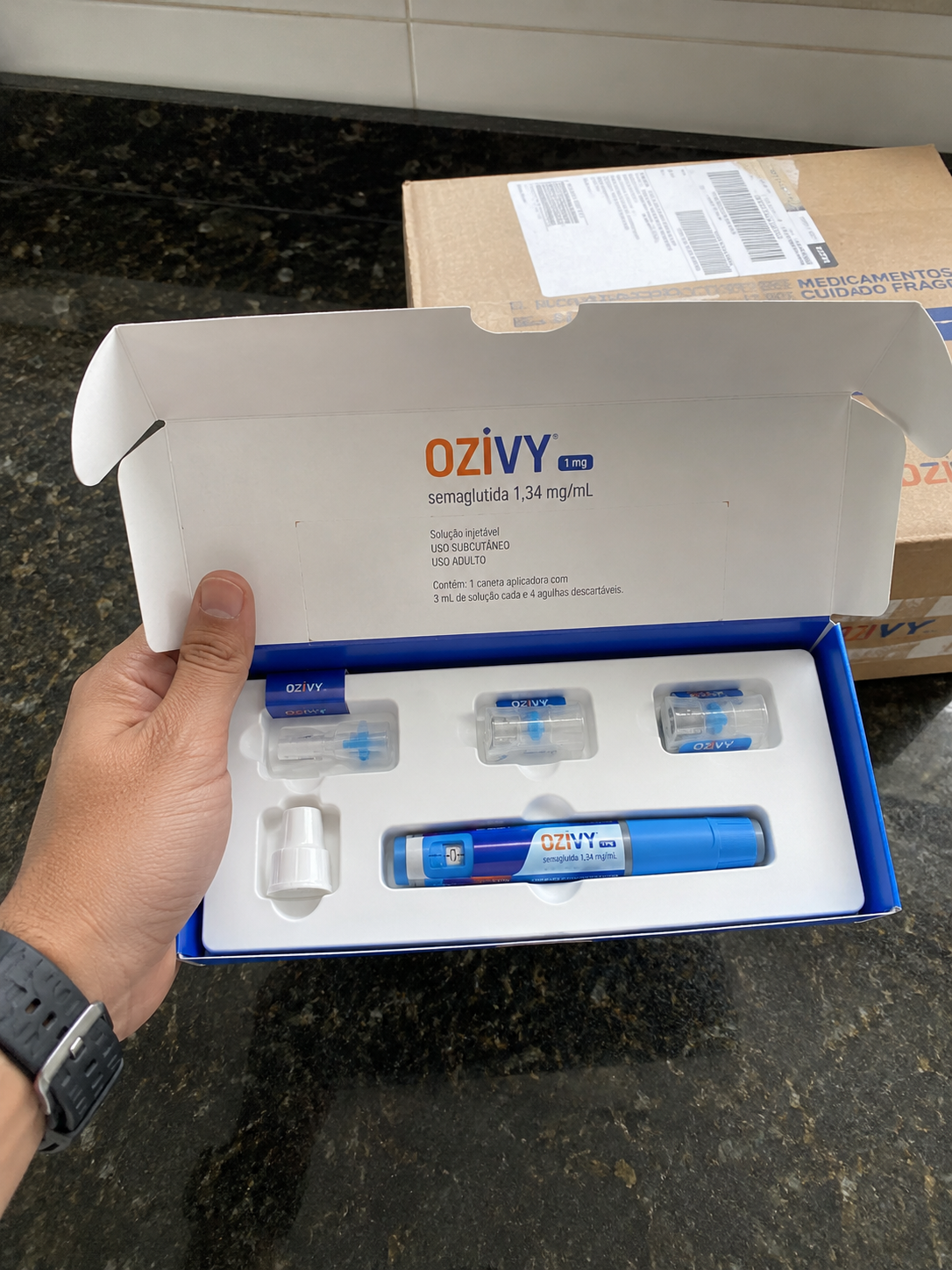 Cliente segurando o kit OZIVY ao lado da caixa de entrega